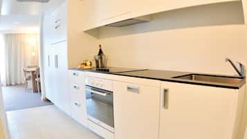 Cozinha moderna com armários brancos, bancada preta e eletrodomésticos de aço inoxidável.