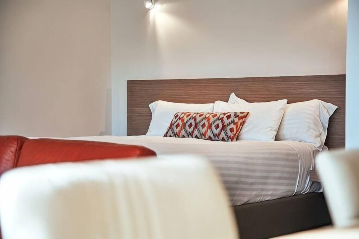 Quarto de hotel com uma cama, cabeceira e mesa de cabeceira.