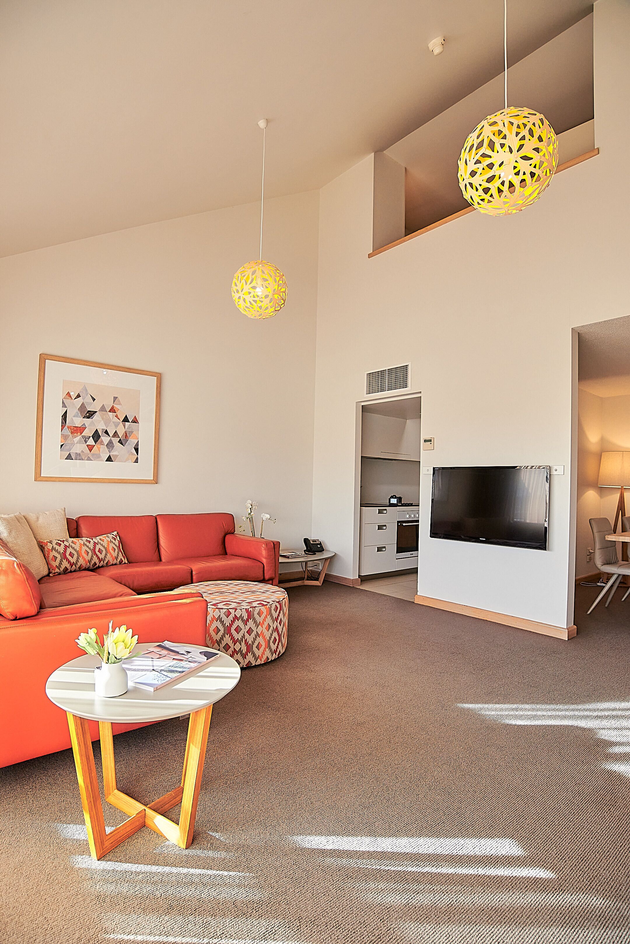 A modern living room with a sofa, a coffee table, a TV, and pendant lights.