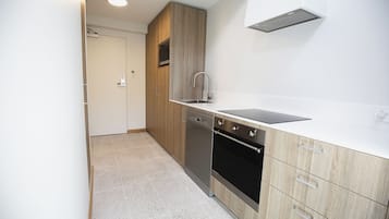 Uma cozinha compacta com armários de madeira, uma máquina de lavar louça e um fogão.