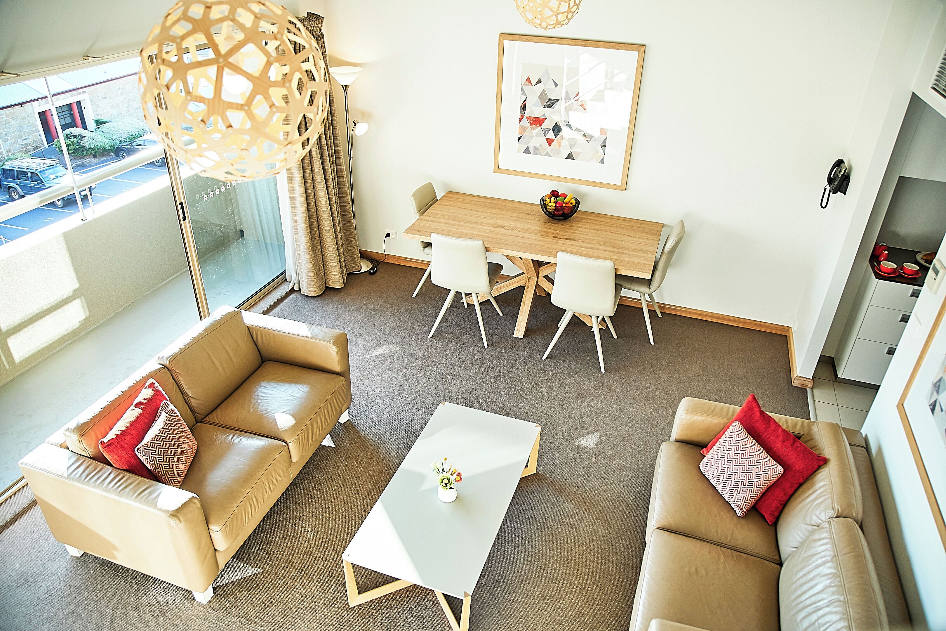 A modern living room with a dining area, a sofa, a coffee table, and a view of the outside.