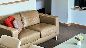 Una sala de estar moderna con un sofá de cuero color beige, una mesa de centro de madera y una obra de arte abstracta enmarcada en la pared.