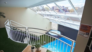 Un balcon avec vue sur une piscine, un jacuzzi et le paysage urbain.