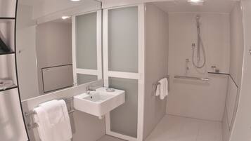 A modern bathroom with a glass-enclosed shower, a white sink, and a mirror.