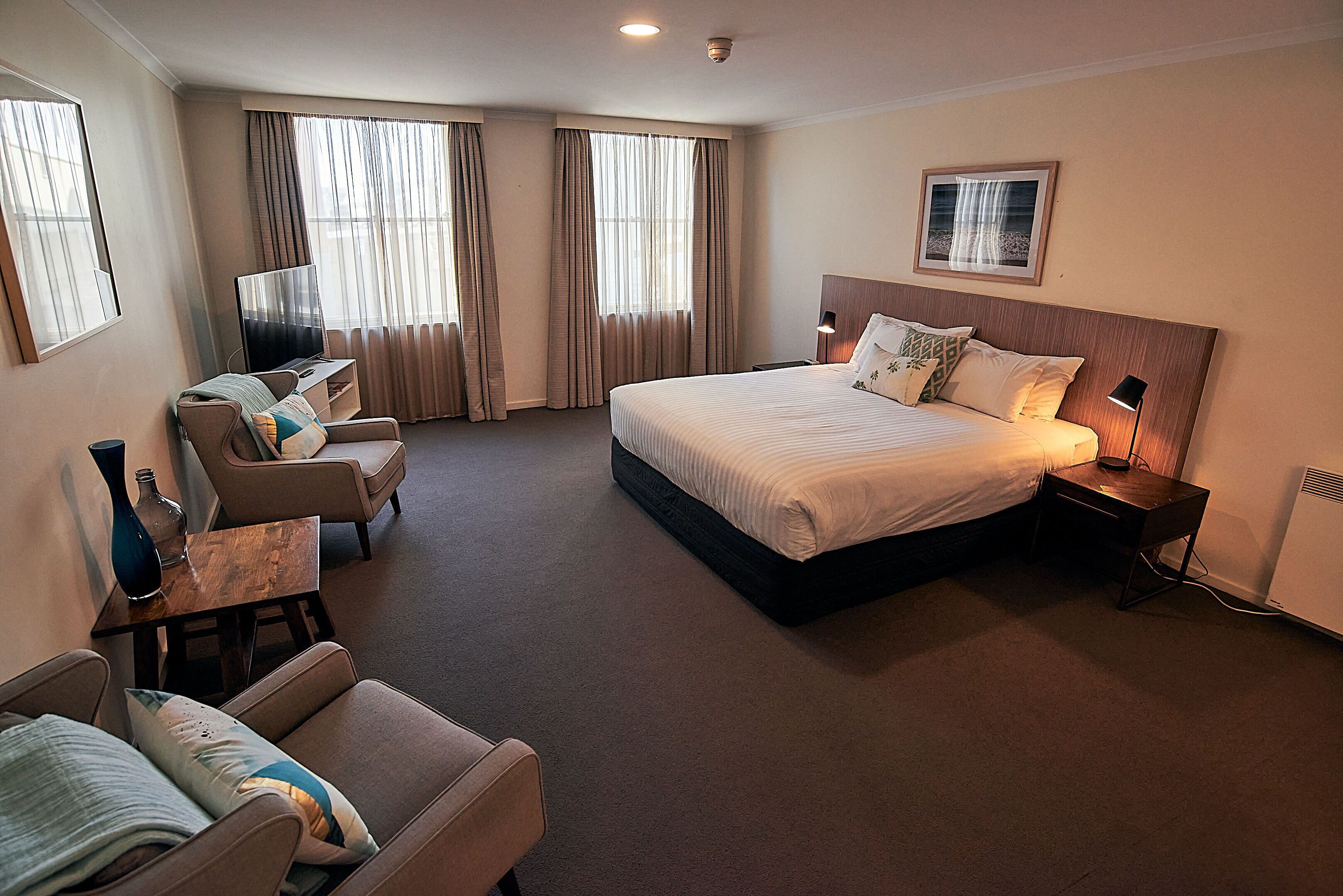 A hotel room with a large bed, a desk, a chair, and a television.