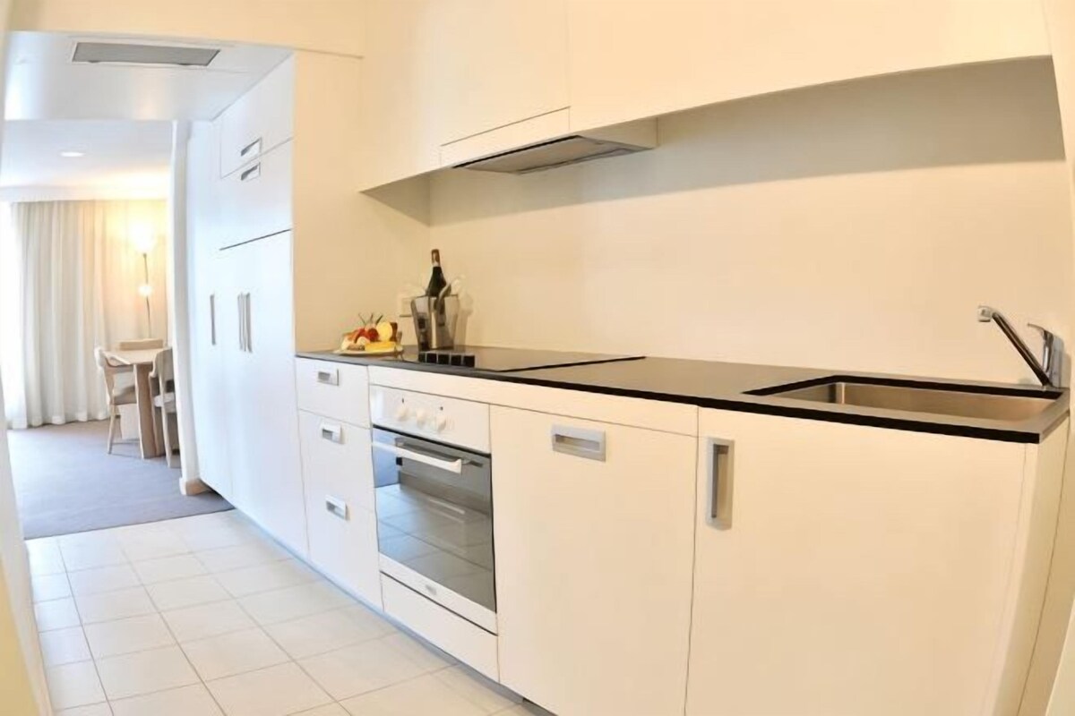 A modern kitchen with a black countertop, stainless steel appliances, and a built-in oven.