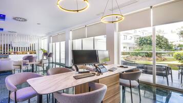 Un moderno vestíbulo de hotel con mostrador de recepción, zona de estar y ventanas amplias que ofrecen vistas al exterior.