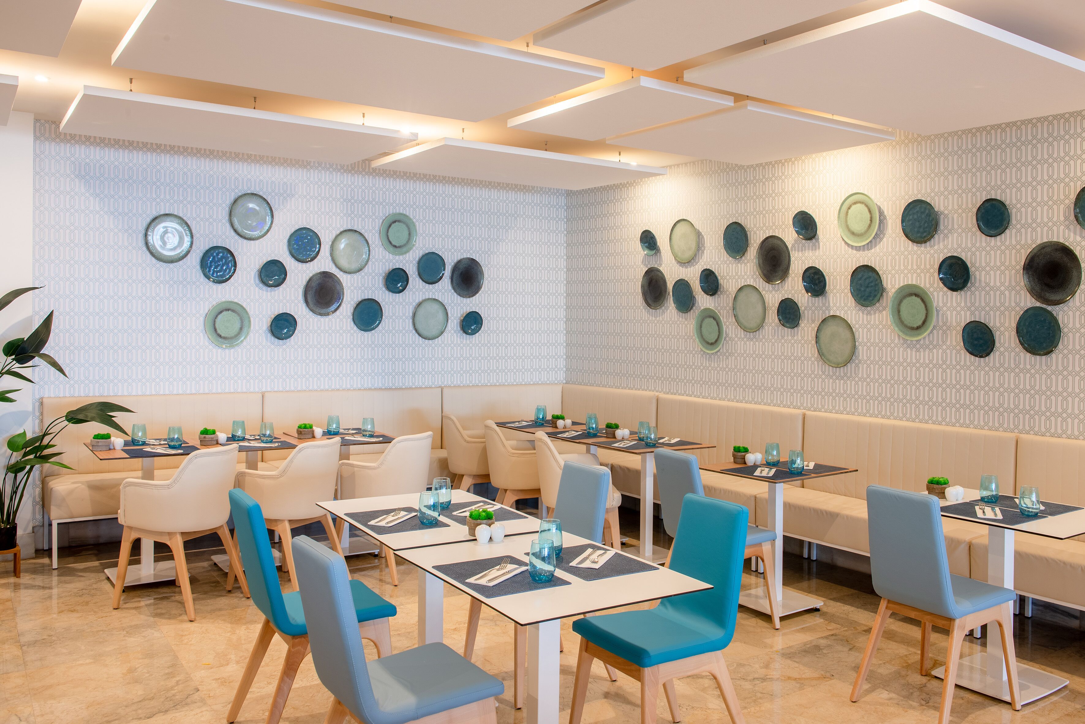 A restaurant with multiple tables and chairs, a patterned wall, and a ceiling with exposed beams.