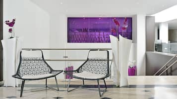 A modern interior with two black and white patterned chairs, a purple decorative wall, and a view of a building through a window.