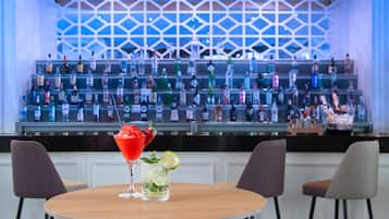 A bar area with a variety of bottles and a cocktail on a table.