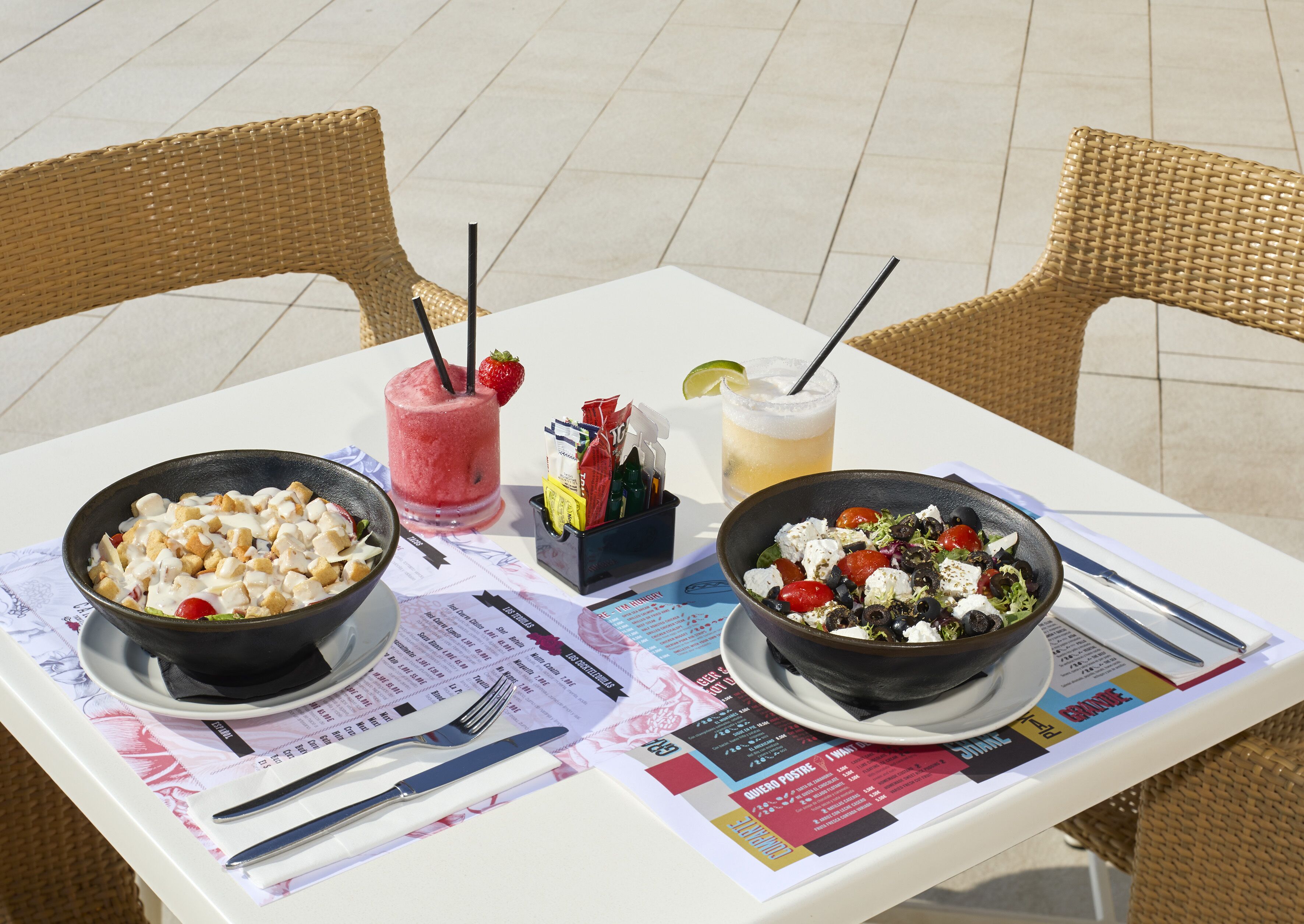 A table with two bowls of food, a drink, and a menu.