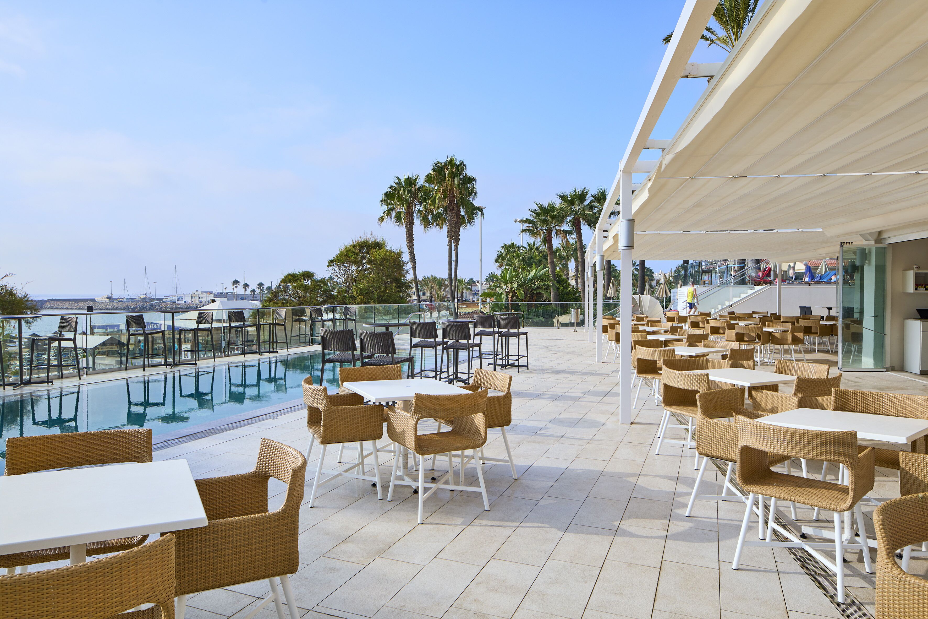 A rooftop pool area with outdoor seating and a view of the ocean.