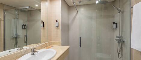 A modern bathroom with a glass-enclosed shower, a sink with a mirror, and a toilet.