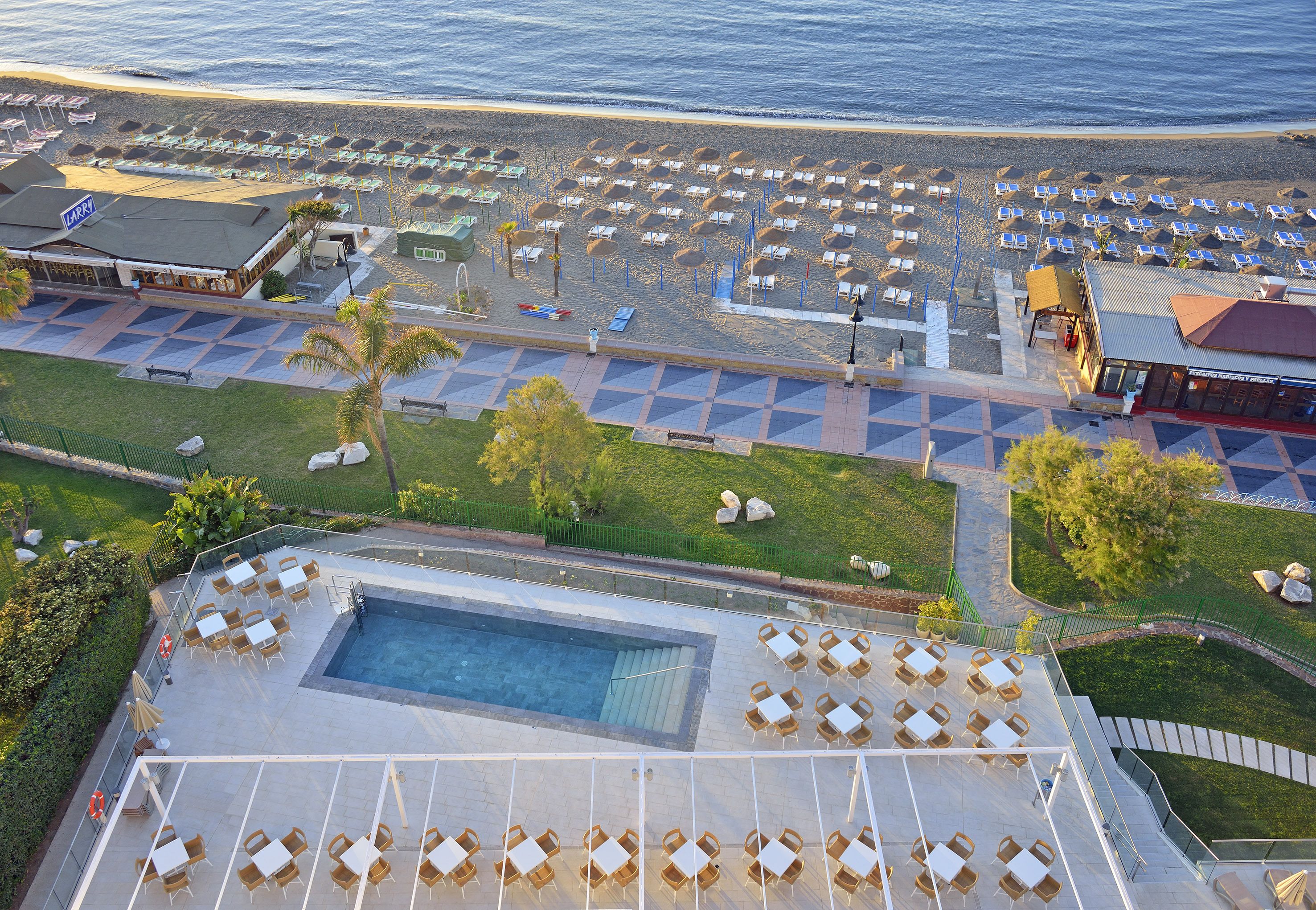 Een resort met een zwembadgedeelte, ligbedden aan het strand en een eetgedeelte.