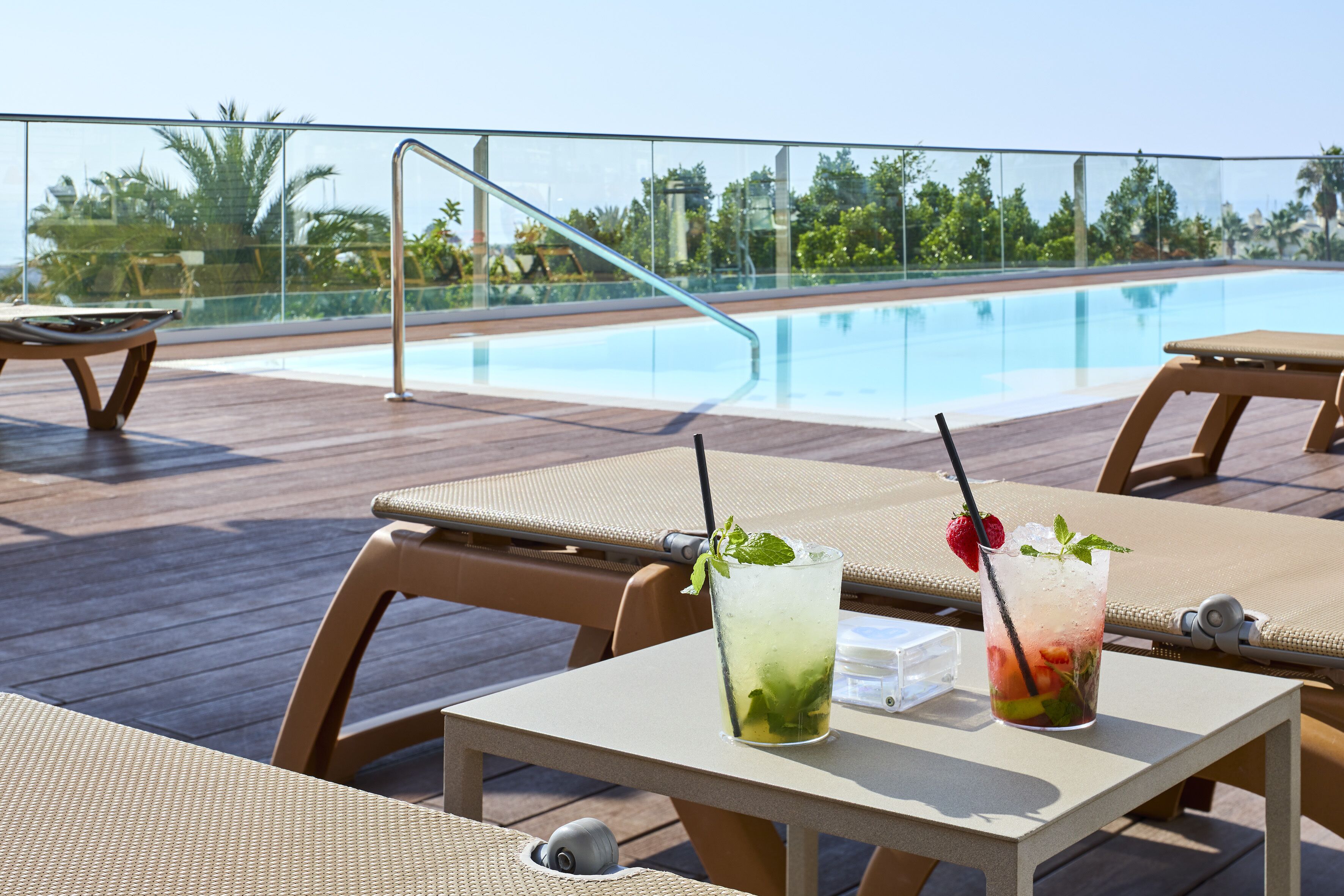 Un espace aménagé au bord de la piscine, avec des chaises longues et une table où sont servis des boissons.