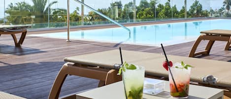 A poolside area with lounge chairs and a table with drinks.