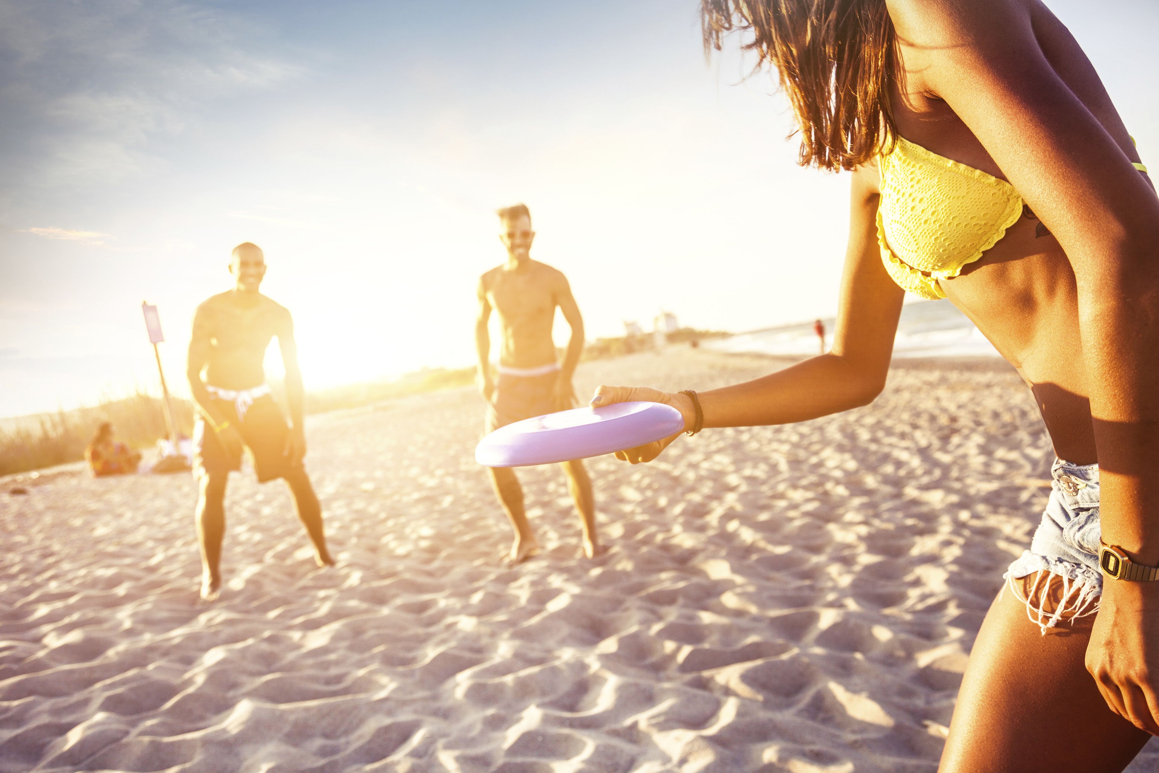 A beach scene with people playing frisbee.