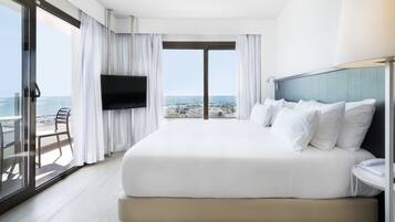 A hotel room with a large bed, a TV, a balcony with a chair, and a view of the city.
