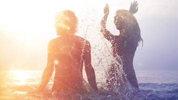 Deux personnes dans l’eau, avec la lumière du soleil en arrière-plan.