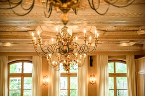 A chandelier in a room with wooden ceilings and large windows.