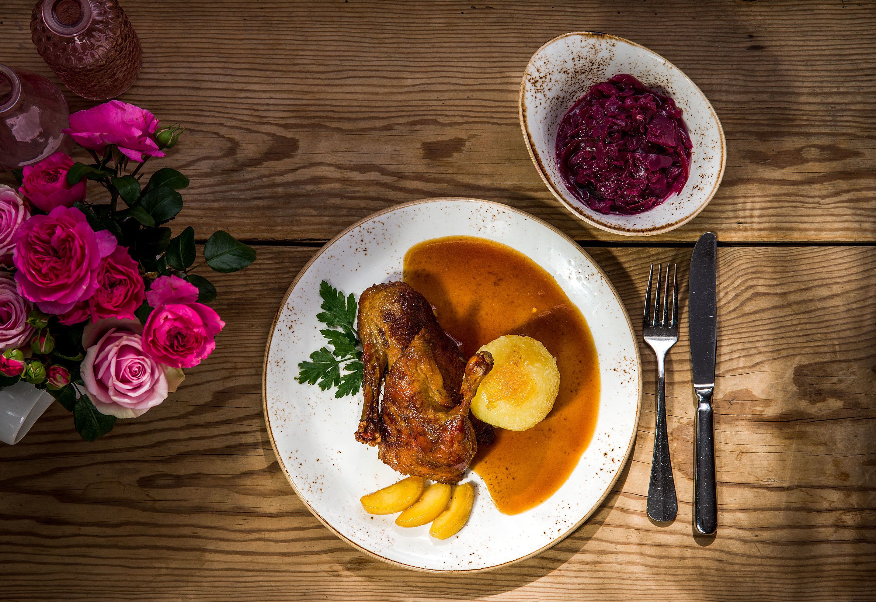 A plate with roasted meat, potatoes, and gravy, accompanied by a bowl of red cabbage.