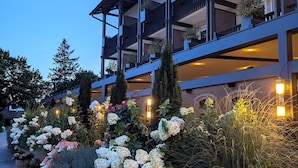Un hotel de varios pisos con balcones, plantas en macetas y un jardín bien cuidado.