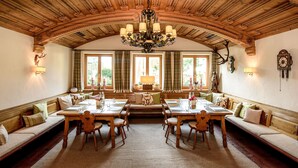 Un comedor con techo de madera alto, candelabros y un gran ventanal con cortinas.