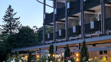 A multi-story hotel with balconies, potted plants, and a well-lit entrance.
