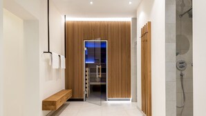Un pasillo moderno con un banco de madera, una puerta de vidrio que da a una habitación y un área de ducha.