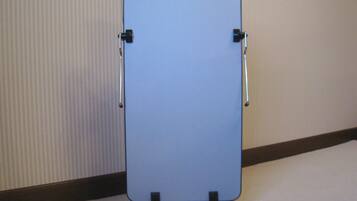 A whiteboard stand with two adjustable arms and a flat surface, mounted on a carpeted floor against a wall with vertical blinds.