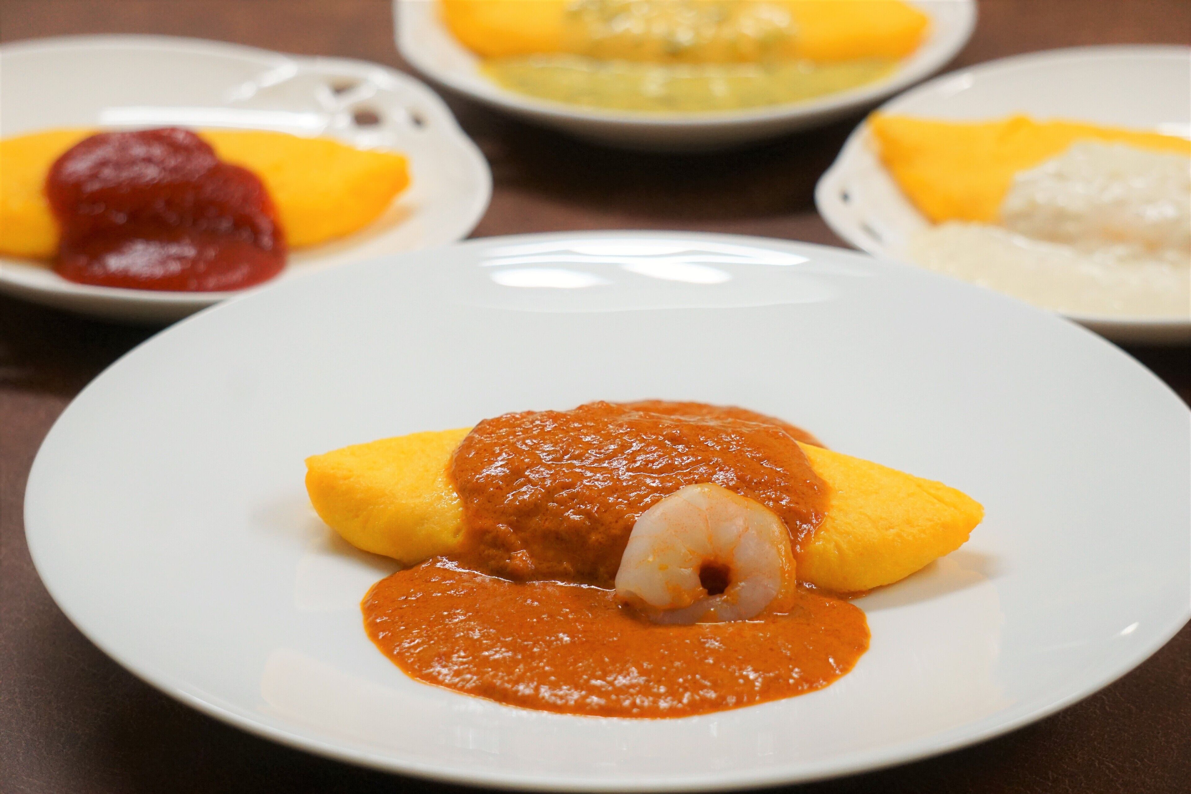 A plate of food with a shrimp and sauce, surrounded by other dishes.