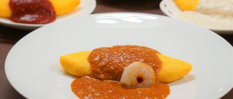 A plate of food with a shrimp and sauce, surrounded by other dishes.