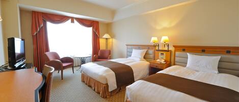 A hotel room with two beds, a desk, a television, and a window with curtains.