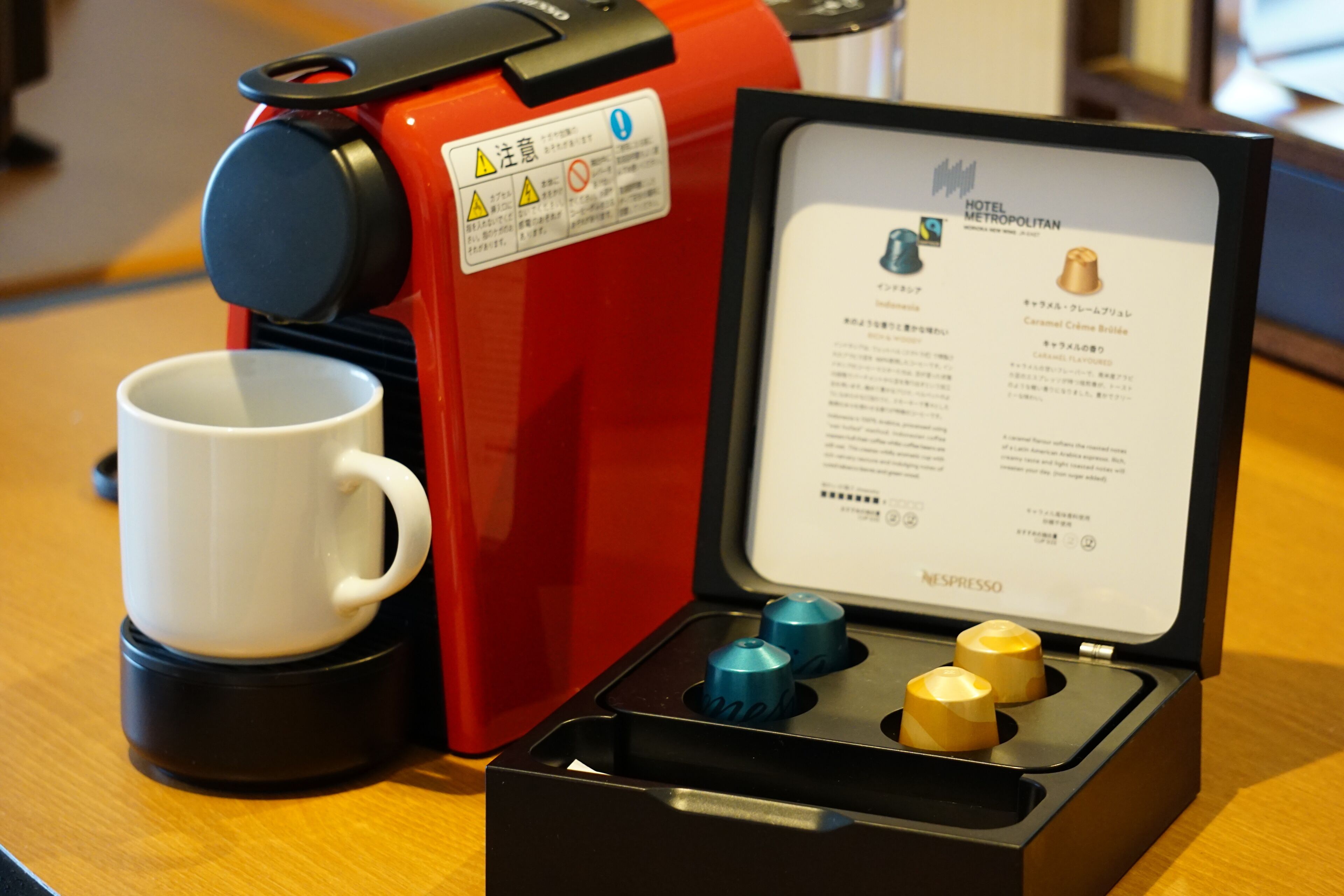 Une machine à café rouge, avec son manuel d’utilisation et une tasse à côté.