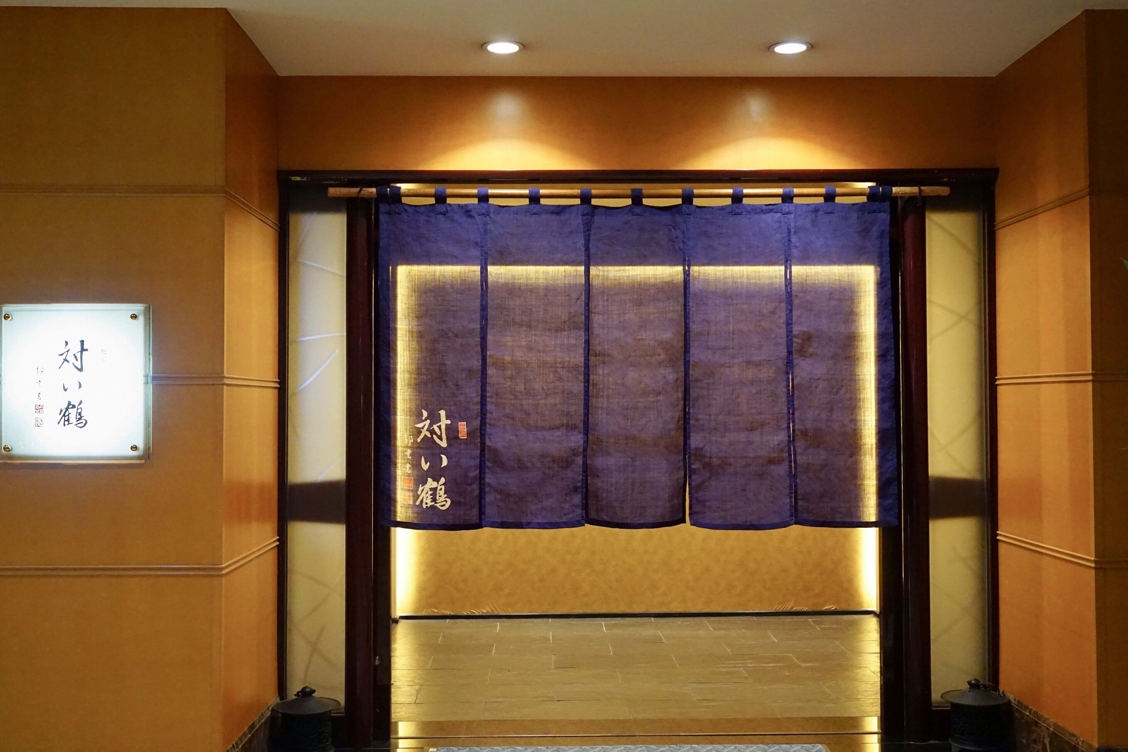 Ein traditioneller japanischer Raum mit Tatami-Boden, Shoji-Schirm und einem Schild mit japanischen Schriftzeichen.