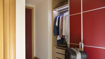 A walk-in closet with hanging clothes and a suitcase.