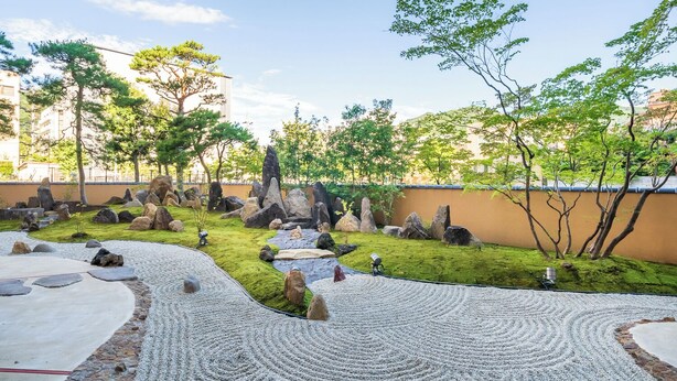 Un jardin aménagé avec un sentier de gravier, des rochers et des arbres.
