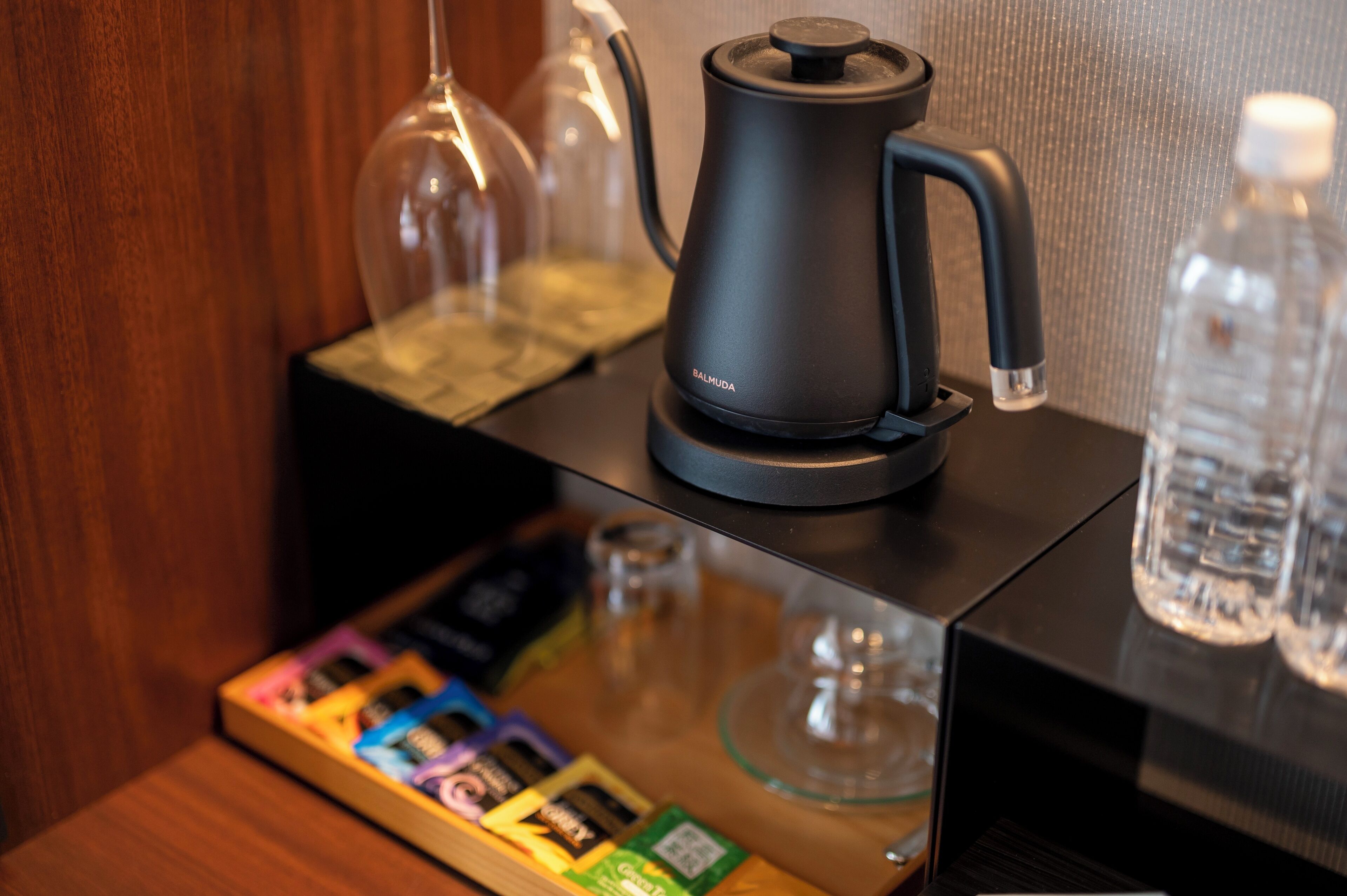 A coffee maker, a glass container, and a water bottle on a table.