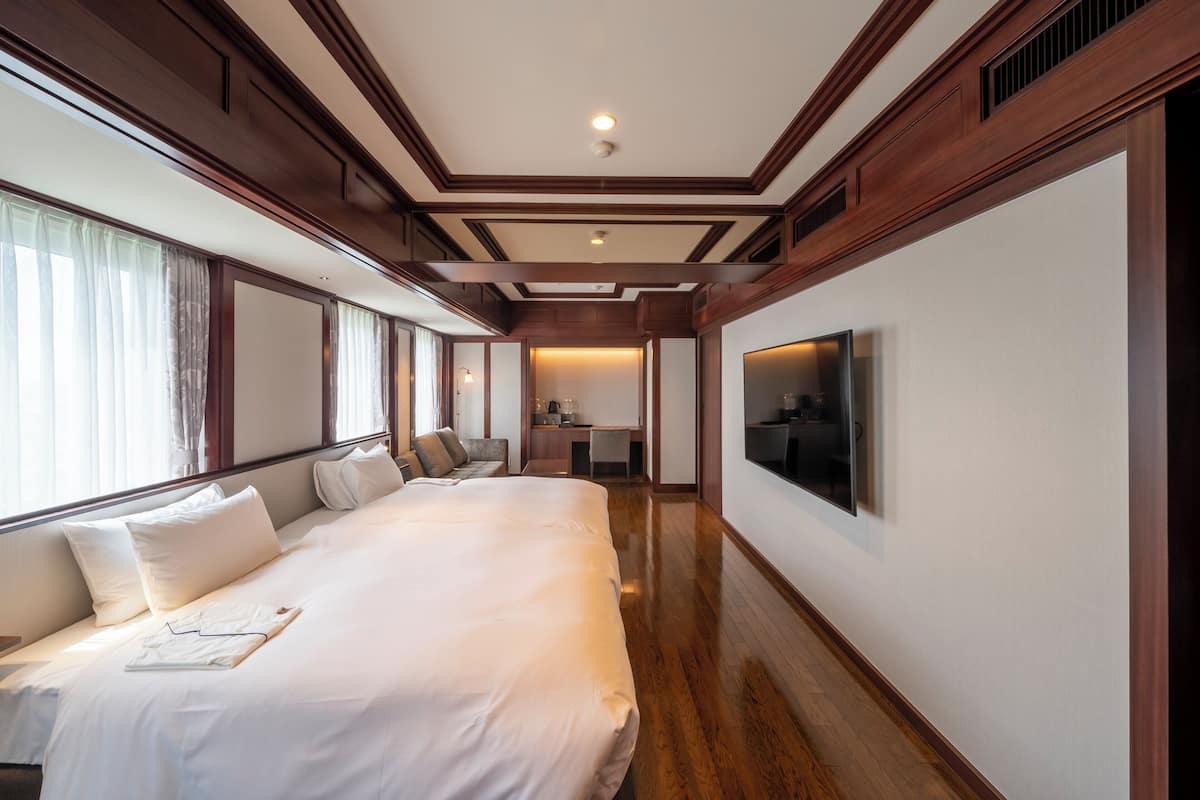 A hotel room with a large bed, a desk, and a television.