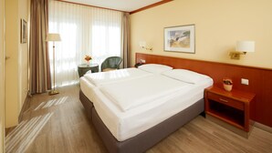 A hotel room with a large bed, a bedside table with a lamp, a chair, and a painting on the wall. - Best Western Hotel Geheimer Rat (Magdeburg)