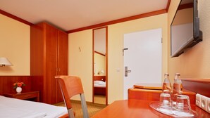A hotel room with a bed, a desk, a chair, a wardrobe, a television, and a mirror. - Best Western Hotel Geheimer Rat (Magdeburg)
