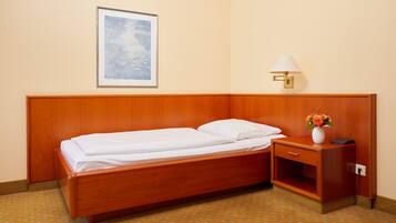 A hotel room with a single bed, a nightstand, a lamp, and a framed picture on the wall.