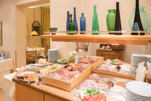 Un bufé con diversas opciones de comida y cristalería decorativa a la vista.