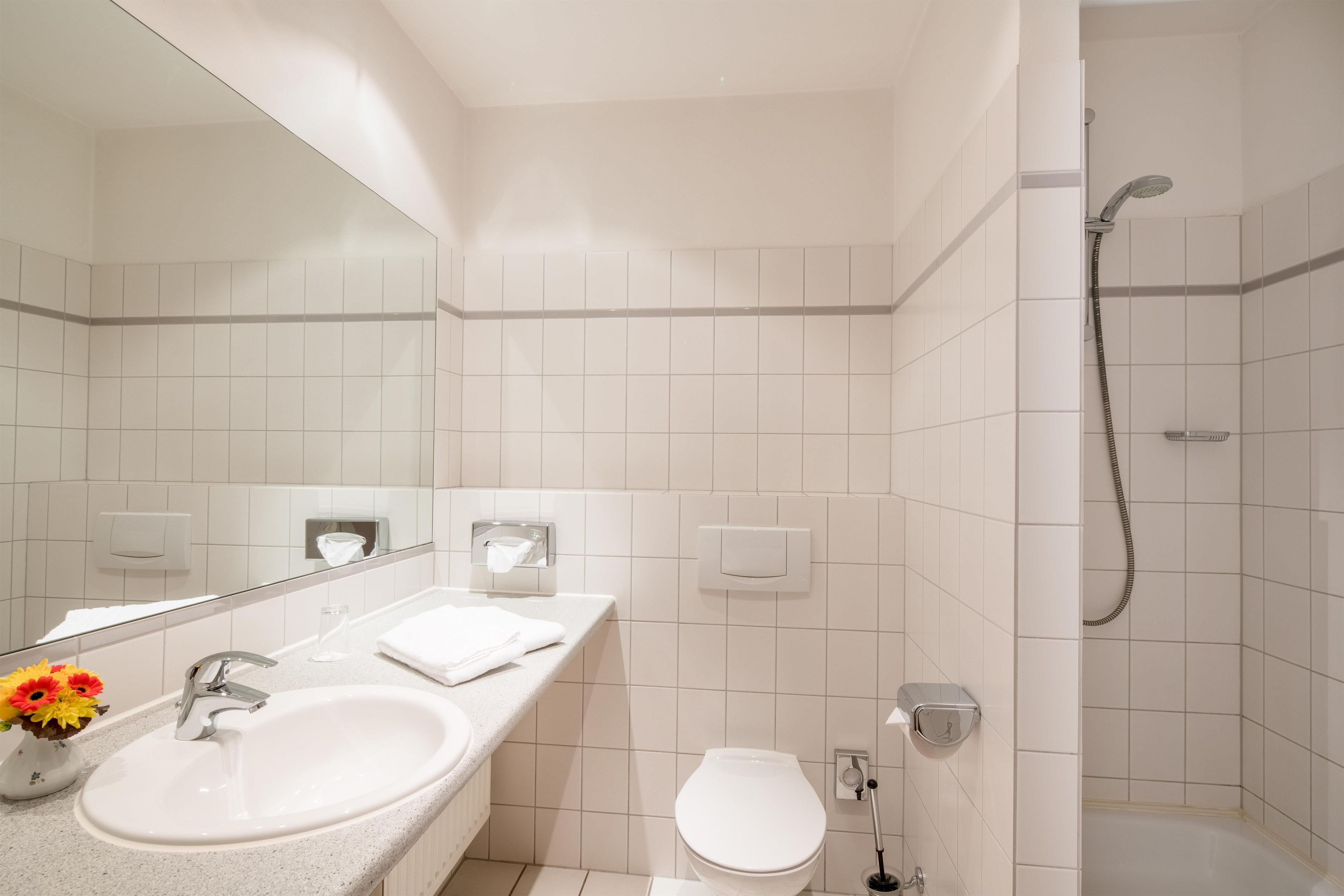 A modern bathroom with a sink, toilet, and shower.