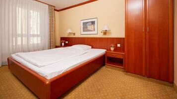 Habitación de hotel con una cama grande, armario de madera, mesitas de noche con lámparas y un cuadro en la pared.