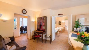 A living room with a sofa, a wooden table, a bookshelf, and a dining area with a table set for two. - Best Western Hotel Geheimer Rat (Magdeburg)