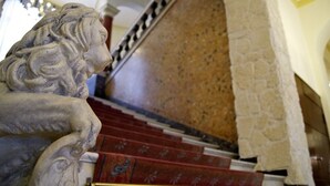 A stone lion statue at the base of a staircase with red steps and a stone wall. - Hotel Deutsches Haus (Braunschweig)