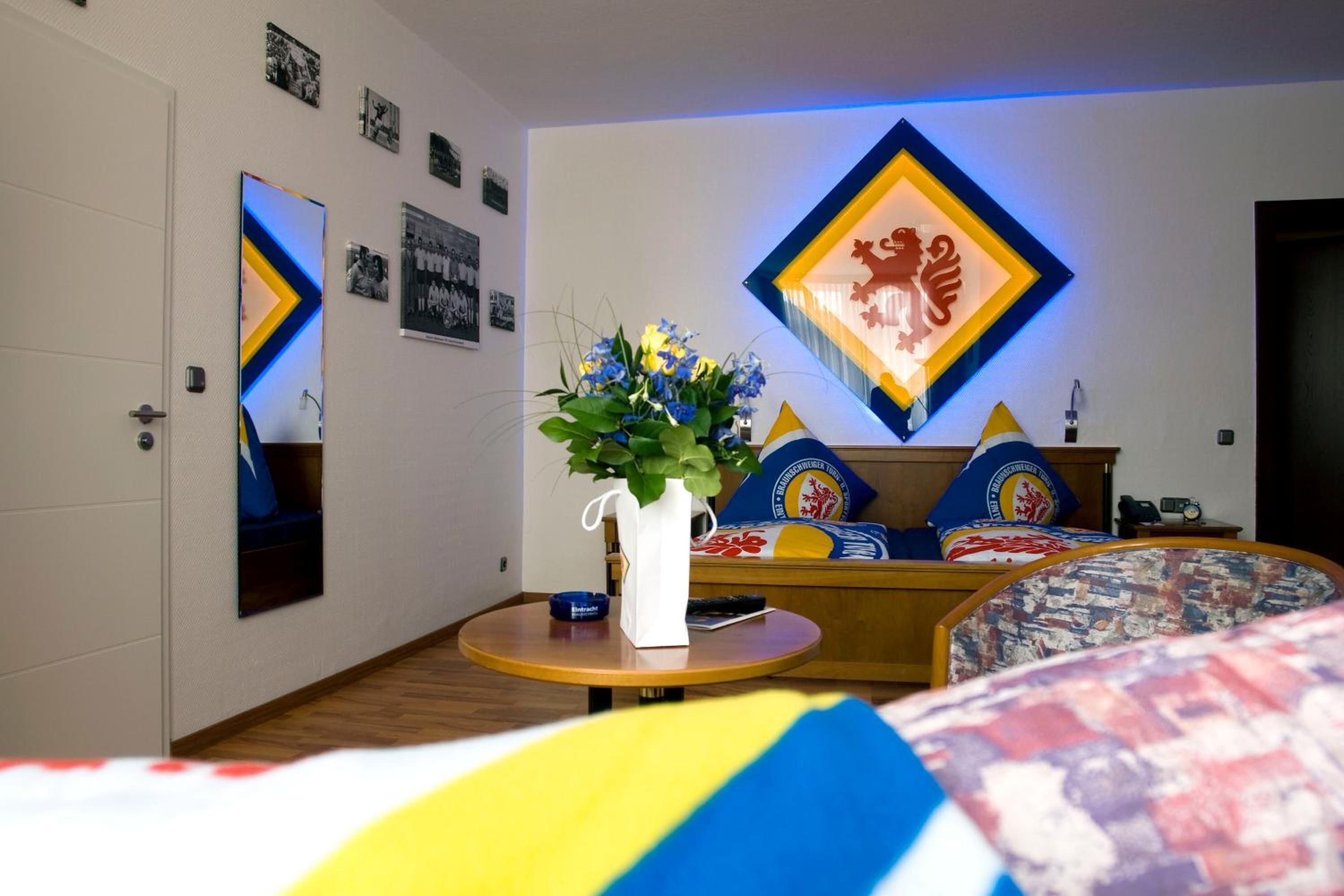 Un dormitorio moderno con cama, mesita de noche con un florero y una lámpara fijada a la pared.