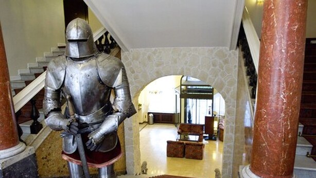 A knight in armor standing on a staircase with marble columns and a polished floor. - Hotel Deutsches Haus (Braunschweig)