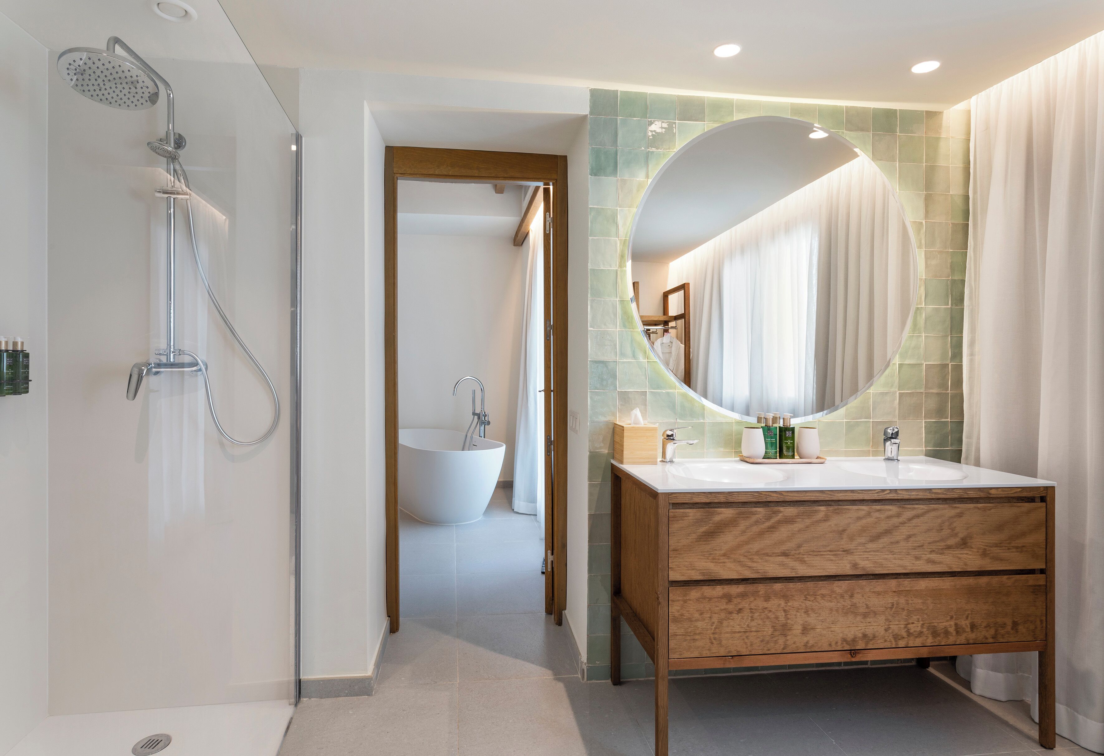 A modern bathroom with a freestanding bathtub, a vanity with a mirror, and a showerhead.